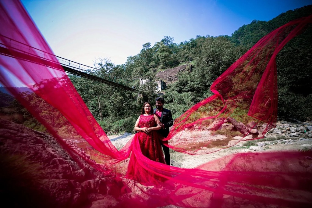 Pre-wedding couple on suspension bridge with dramatic flying red gown