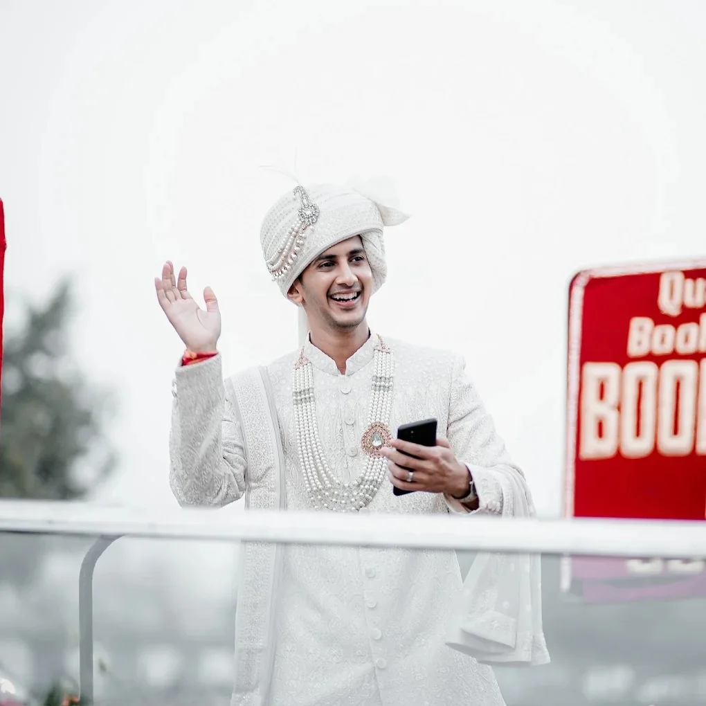 Candid groom in royal ivory sherwani waving joyfully during wedding by Wedding Shedding