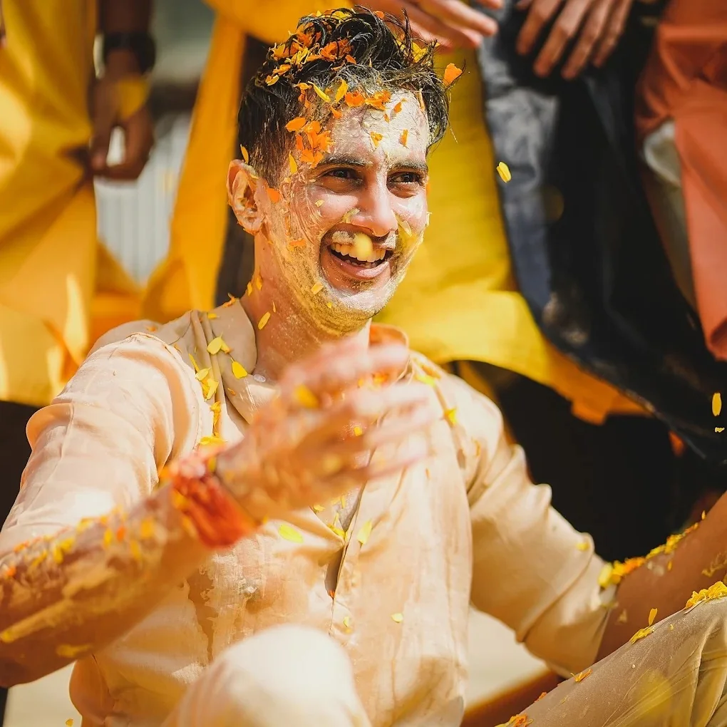 Joyful groom celebrating Haldi with yellow turmeric by Wedding Shedding