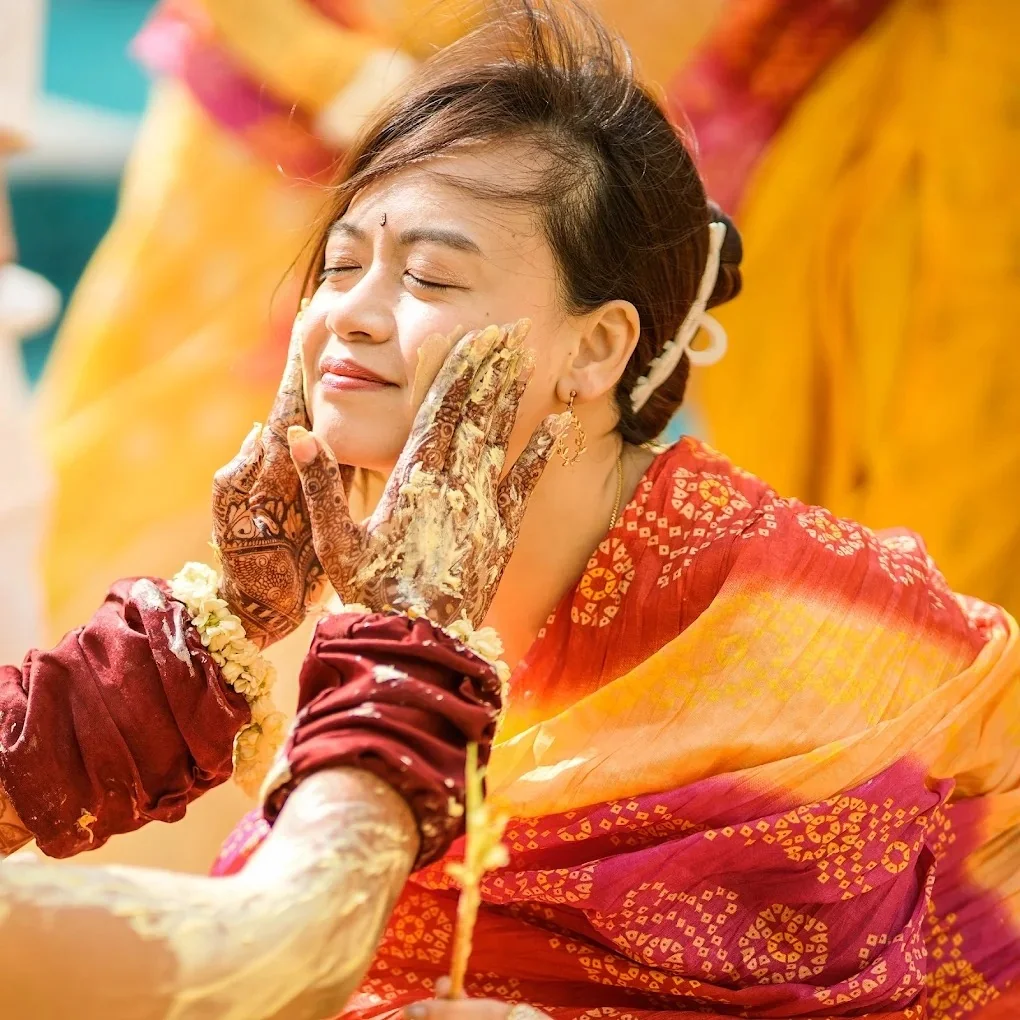 Bride in yellow receiving auspicious haldi blessings with marigolds