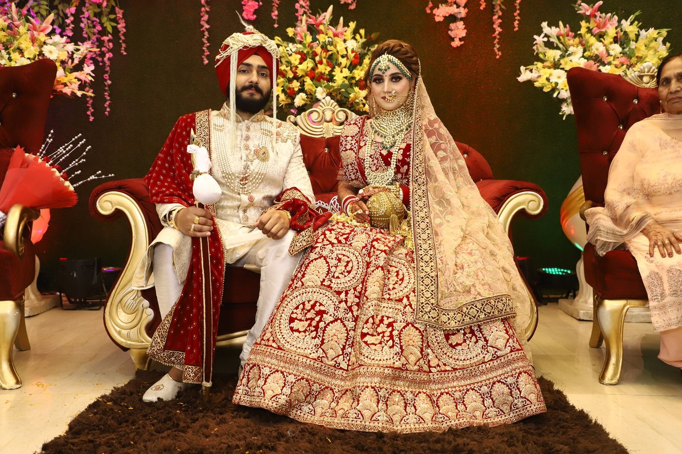 Bride and groom on royal wedding stage surrounded by golden floral decor